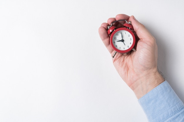 Mechanical red alarm clock in male hands on white background. Time management concept. Top view