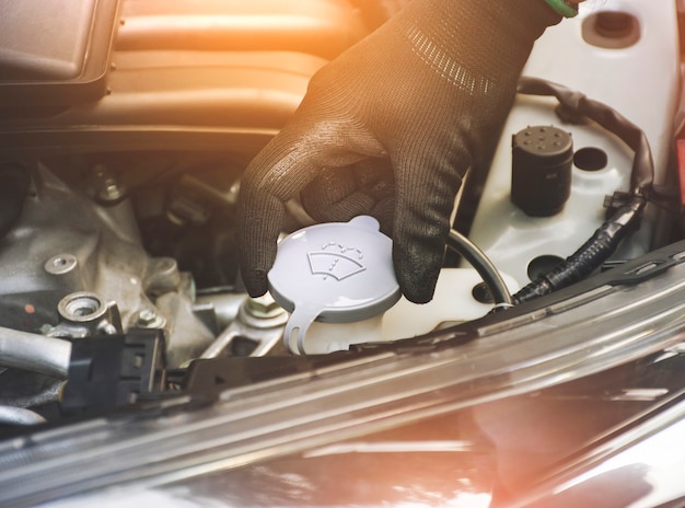 The mechanics hand was open or closed cap to the water reserve tank of the car wiper