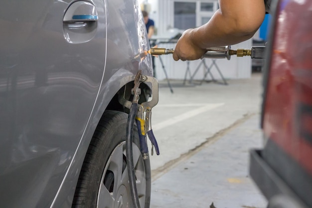 Le mani dei meccanici riparano le ammaccature sulla carrozzeria dell'auto con uno speciale dispositivo di aspirazione