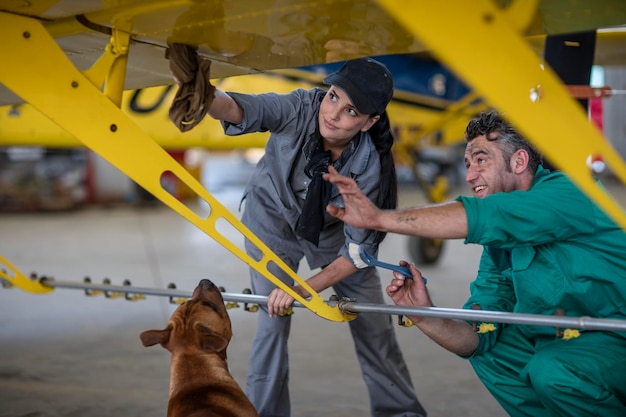 Mechanics with dog in hangar repairing light aircraft