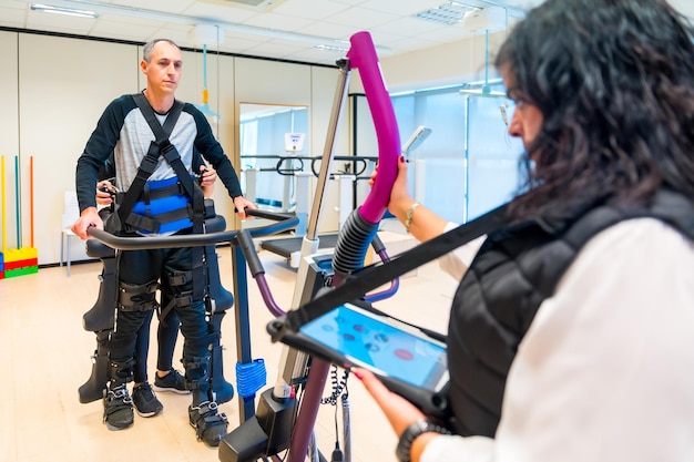 Foto mechanisch exoskelet vrouwelijke fysiotherapie medische assistent met gehandicapte persoon opgeheven met robotskelet futuristische rehabilitatie fysiotherapie in een modern ziekenhuis