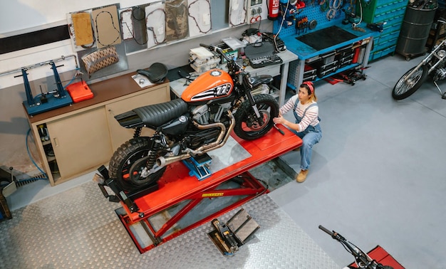 Foto mechanische vrouw die een op maat gemaakte motorfiets over het platform bekijkt