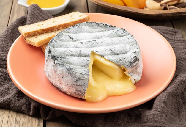 Mected brazilian artisan Lua Cheia cheese with toasts fruits and nuts over wooden table