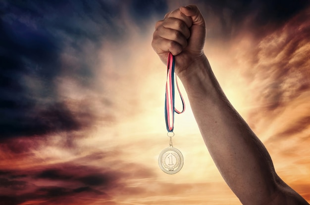 Medaille voor de eerste plaats in de hand van de atleet tegen een dramatische lucht