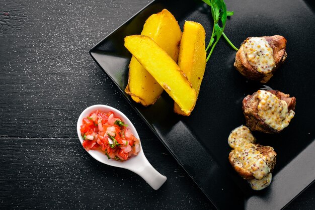 Medallions of pork with potatoes on a wooden background Top view Free space for text