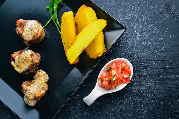 Medallions of pork with potatoes on a wooden background Top view Free space for text