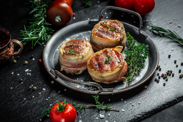 Medallions steaks from the beef tenderloin covered bacon on metal tray on Dark background. Top view.