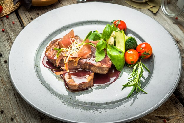 Medallions of veal, with sauce on a plate. Wooden background