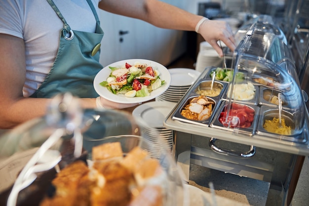 Medewerker luchthavencafé voegt meer eten toe aan het bord