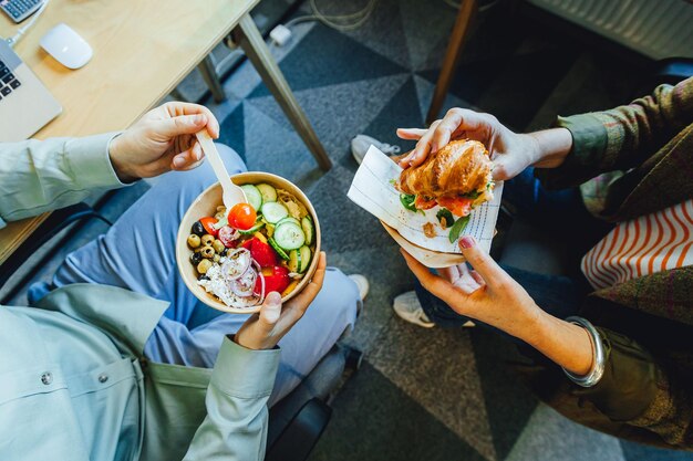 Medewerkers genieten van een gezonde lunch in de kantoor salade schaal en croissant broodje