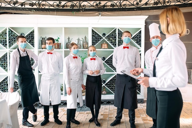 Medewerkers van een restaurant of hotel met beschermende maskers. Einde quarantaine. Restaurantmanager en zijn personeel op het terras. interactie met de chef-kok in het restaurant.