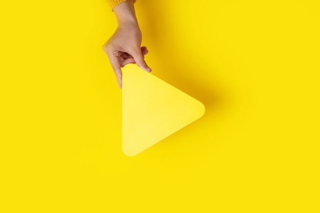 Media player button icon in hand over yellow background