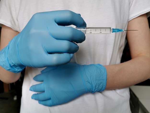 Medic in blue gloves holds a syringe. Disease treatment. 2020 coronavirus vaccine.