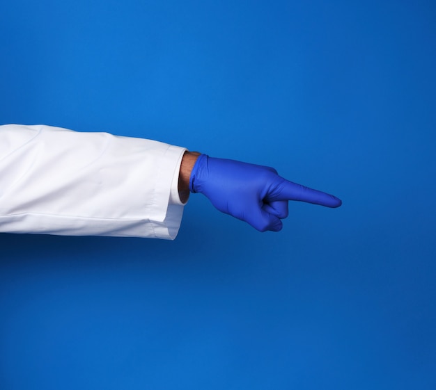 Medic in witte jas, gekleed in blauwe steriele handschoenen, handgebaar met vermelding van het onderwerp, blauwe achtergrond