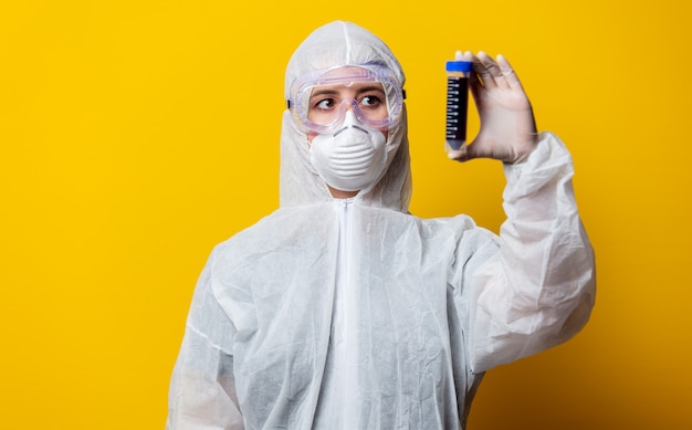 Medic in protection suit and mask holds jar with blood