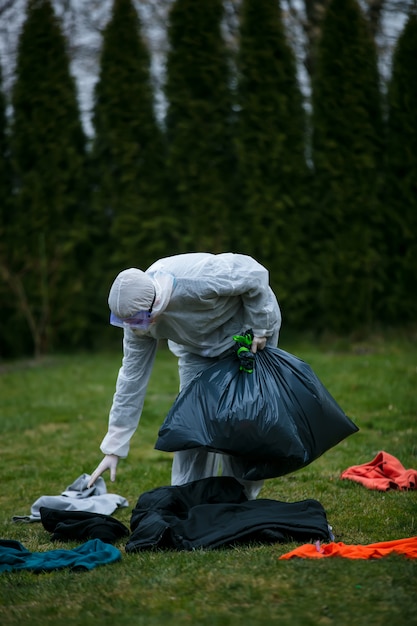 Medic in a protective suit collects things left by infected people in bags