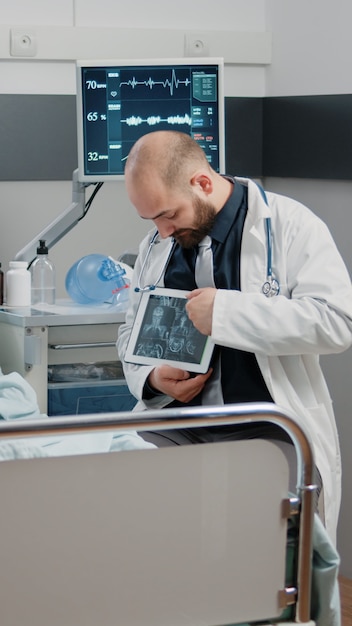 Medic wijzend op tablet-display met radiografie voor zieke vrouw