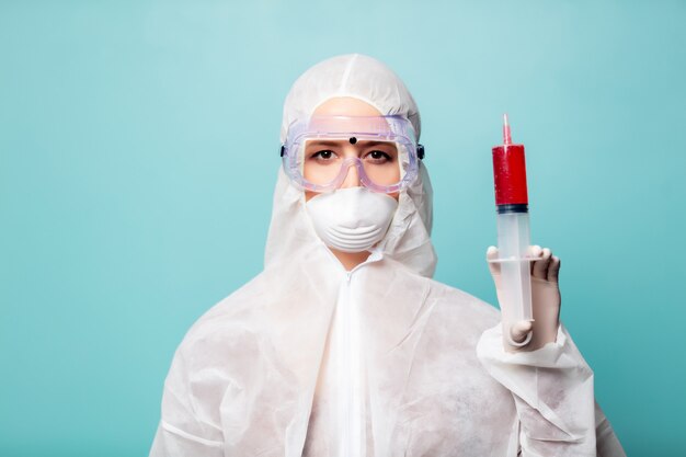 Medic woman wearing protective clothing against the virus with big syringe