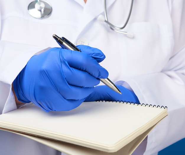 Medic woman in white coat, blue latex gloves holding an open notebook