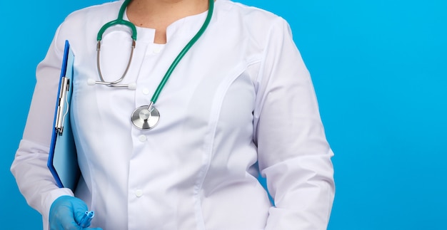 Medic woman in white coat, blue latex gloves holding a tablet with a clip for papers