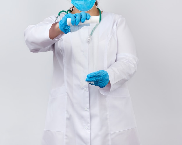 Medic woman in white coat and mask holds a twisted gauze bandage for dressing wounds