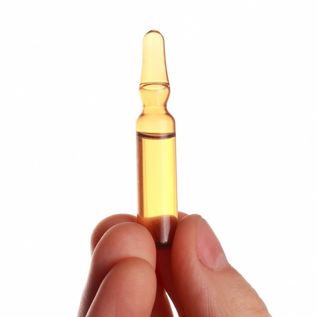 Medical ampoule in a hand on white background