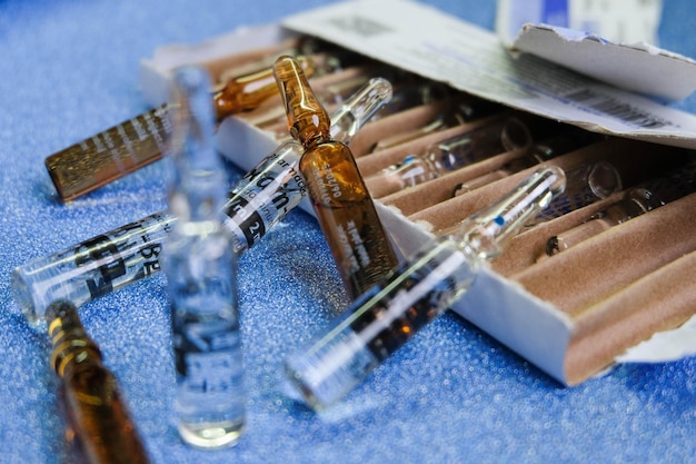 Medical ampoules full of medicine and their box on a blue background