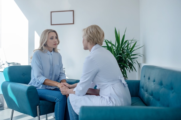 Medical appointment. Blonde female doctor soothing female patient