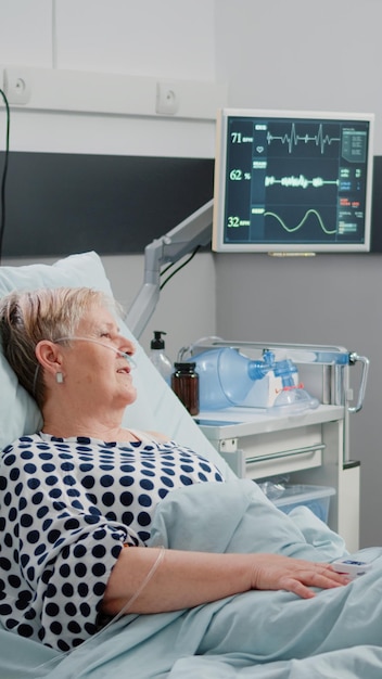 Medical assistant doing consultation with retired patient in hospital ward bed. Nurse talking to ill woman for healthcare treatment and disease, giving assistance and support for recovery