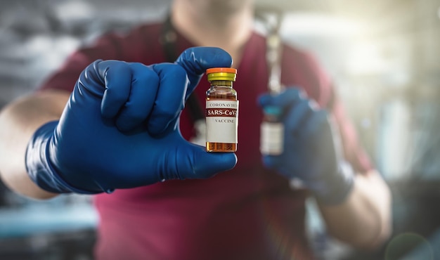 Medical assistant hand in gloves holding vaccine or anesthesia vial bottle in the surgical office