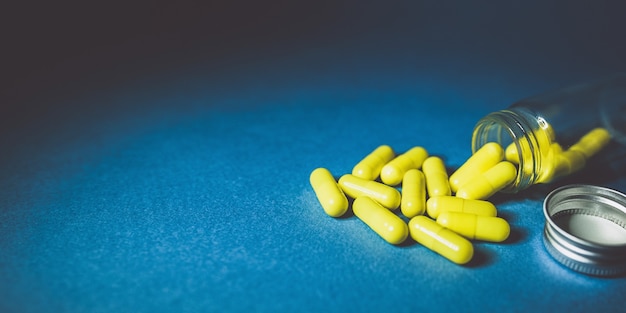 Medical background. Pills tablets in a glass jar on a blue background. Medicine, health care, flu concept. Long web format