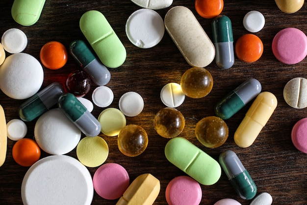 Medical background of various colorful medications on a textured wooden