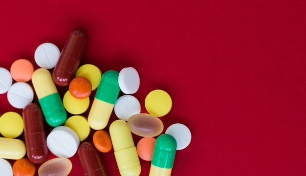 Foto sfondo medico con pillole e capsule su sfondo rosso.