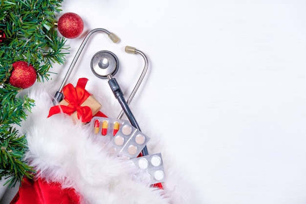 Medical banner with pills gift present box stethoscope and christmas tree on white wooden background