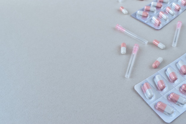 Medical capsules and needles on a gray background