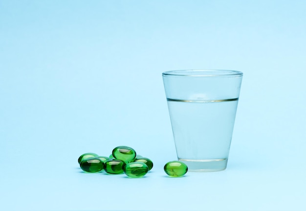 Medical capsules pills and glass water on a blue background