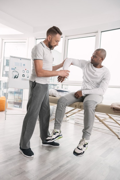 Medical checkup. Nice smart therapist standing near his patient while examining him