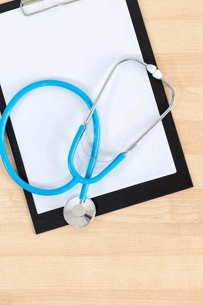 Medical clipboard and stethoscope on wooden desk background Top view Workplace of a doctor