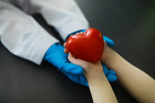 医療の概念。手袋をはめた医師が患者の手を握ります。彼の患者への医者の道徳的な助け。心臓専門医の相談。エピデミック。