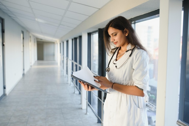 Medical concept of Indian beautiful female doctor in white coat with stethoscope, waist up. Medical student.