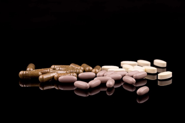 Medical concept of prescription pills and capsules on black background with reflection copy space