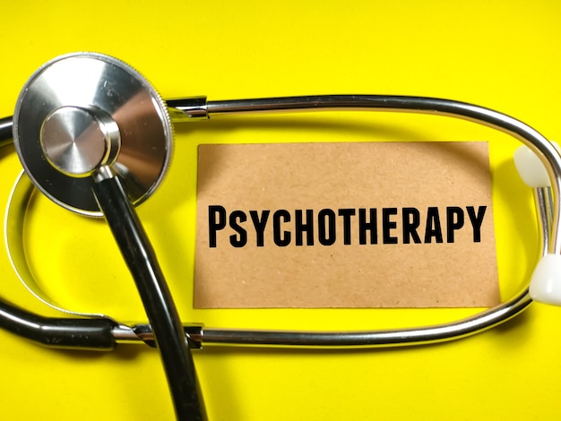 Medical concept Text PSYCHOTHERAPY on brown card with stethoscope on yellow background