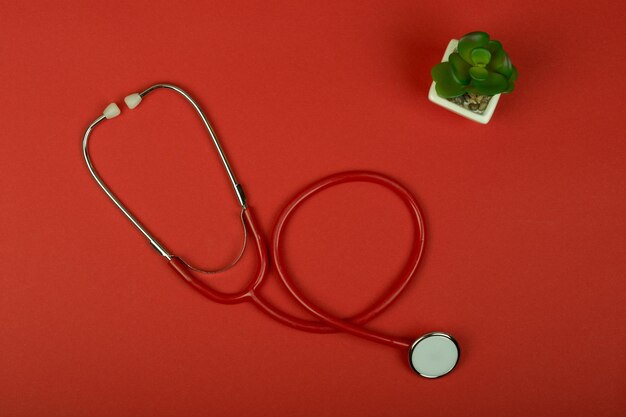 Medical concept top view red stethoscope on red paper background