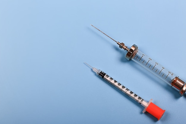 Фото Медицинская концепция два шприца для инъекций на синем фоне инсулина и ретро железный шприц