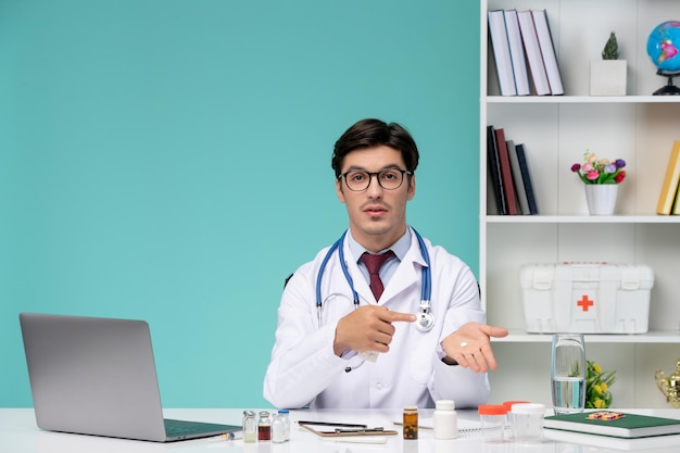 Medical cute smart doctor in lab coat working remotely on computer holding white pill