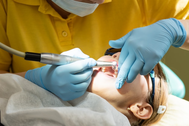 Foto procedura del dentista medico di lucidatura dei denti. bambino che ha pulizia dentale professionale o lucidatura nell'ufficio del dentista. ragazza che visita il dentista