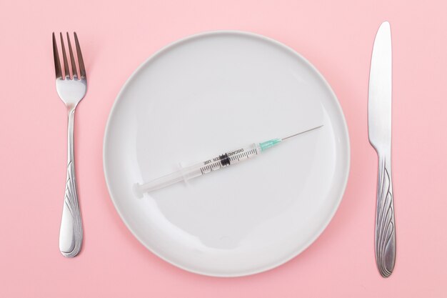 Medical disposable syringe on white ceramic plate