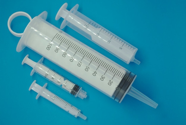 Medical disposable syringes of different volumes on a blue background.