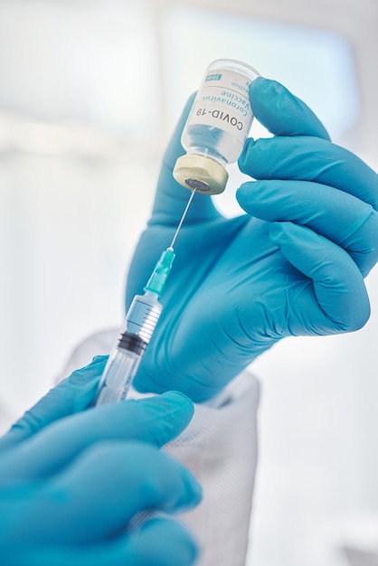 Medical doctor holding covid vaccine giving injection during checkup and preparing needle for consultation Closeup of the hands of a heathcare worker expert or professional working at hospital