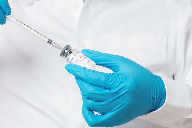 Medical doctor holding tube with Coronavirus vaccine and syringe.